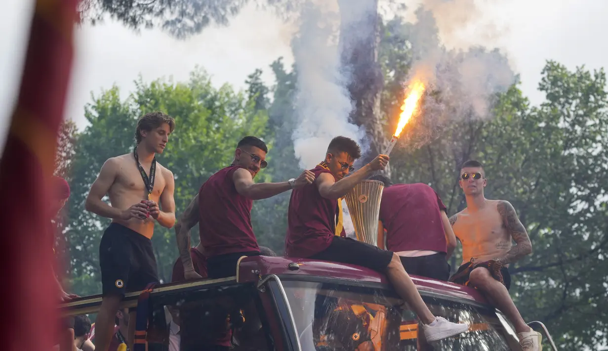 Penyerang AS Roma, Stephan El Shaarawy memegang trofi dan suar saat ia duduk bersama rekan satu timnya di bus di tengah kerumunan pendukung yang gembira merayakan kemenangan juara Liga Konferensi Eropa UECL di depan Colosseum di Roma (26/5/2022). (AP Photo/Gregorio Borgia)