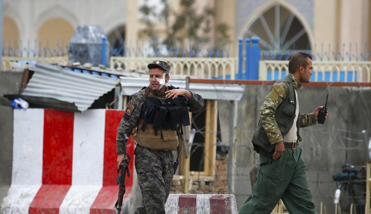 Seorang anggota pasukan keamanan yang terluka meninggalkan lokasi ledakan bom mobil bunuh diri di Kabul, Afghanistan, Selasa (19/4). Ledakan tersebut menyebabkan puluhan orang tewas dan sekitar 150 lainnya terluka. (REUTERS/Omar Sobhani)