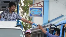 Manny Pacquiao memberikan baju ke pendukungnya selama kampanye di kota Calamba, Provinsi Laguna, selatan Manila (28/4). Manny Pacquiao menjadi salah satu politisi Filipina yang paling kuat di negaranya. (AFP PHOTO/TED aljibe)