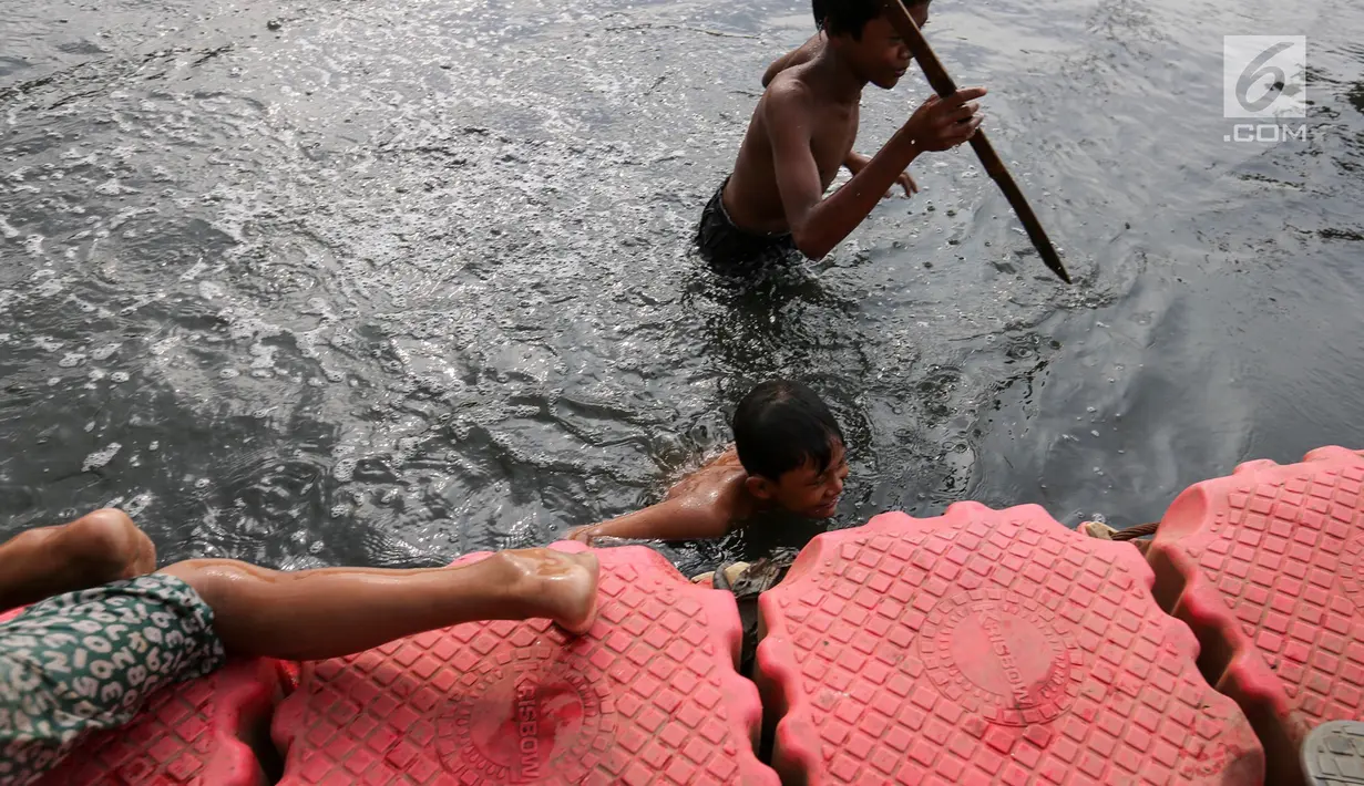 Anak-anak mencari ikan menggunakan bambu runcing di Kanal Banjir Barat (KBB) Petamburan, Jakarta, Senin (12/8/2019). Surutnya debit air KBB akibat musim kemarau dimanfaatkan anak-anak untuk bermain sambil mencari ikan. (Liputan6.com/Fery Pradolo)