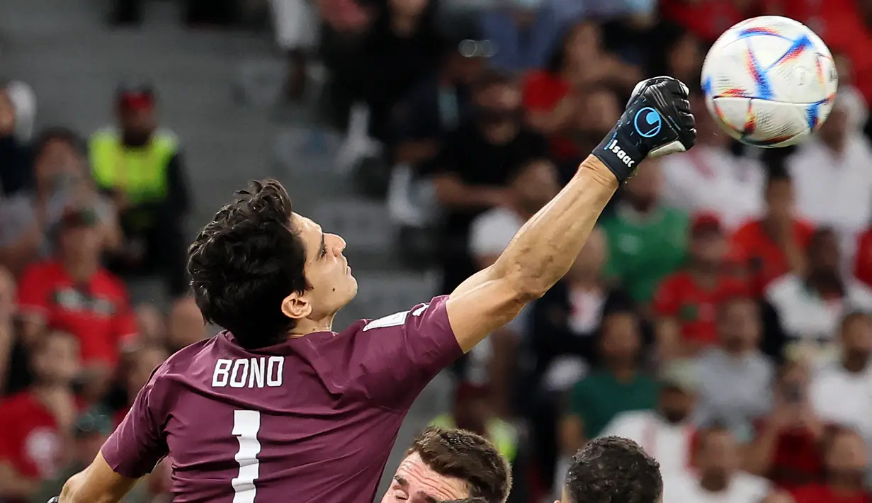 Kiper Maroko #01 Yassine Bounou (Kiri) membelokkan tembakan dari serangan pemain Spanyol pada babak 16 besar Piala Dunia 2022 di Education City Stadium, Al Rayyan, Rabu (6/12/2022) dini hari WIB. Adapun penampilan gemilang saat adu penalti laga Maroko vs Spanyol mengantar Bounou mengukir sejarah Piala Dunia. (KARIM JAAFAR / AFP)