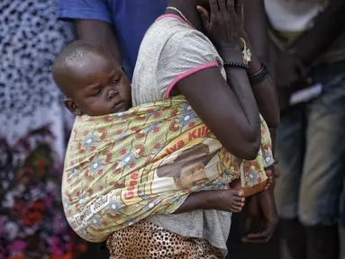 Pengungsi Sudan Selatan menggendong anaknya di sebuah pusat transit pengungsi di Kuluba, Uganda utara, Kamis (8/6). Mereka melarikan diri dari perang saudara di Sudan Selatan yang telah memakan korban puluhan ribu jiwa. (AP Photo / Ben Curtis)