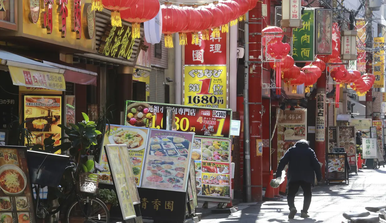Seorang pria melintasi Chinatown yang dihiasi pernak-pernik Imlek di Yokohama, Prefektur Kanagawa, dekat Tokyo, Selasa (9/2/2021). Yokohama Chinatown adalah kawasan pecinan terbesar di Jepang, terletak di pusat kota Yokohama. (AP Photo/Koji Sasahara)