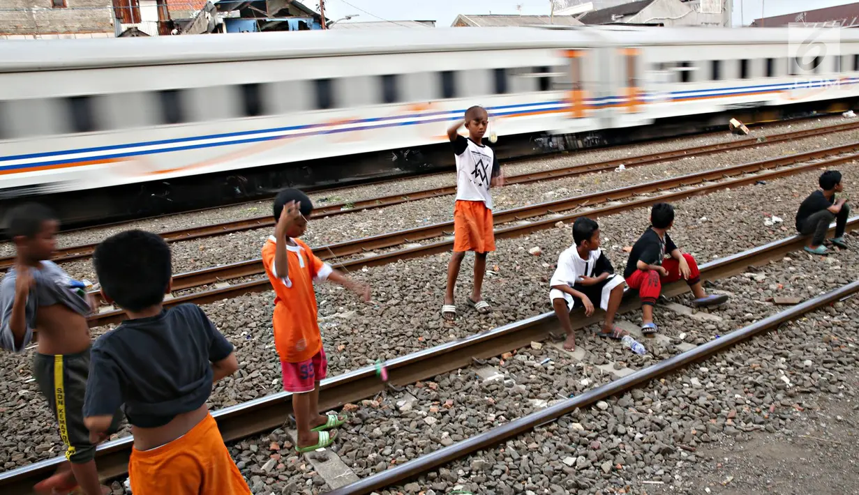 Kereta melintas di kawasan Kemayoran, Jakarta, Senin (24/7). Minimnya lahan bermain menyebabkan anak-anak terpaksa bermain di lokasi tersebut, meskipun berbahaya bagi keselamatan. (Liputan6.com/Immanuel Antonius)