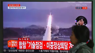 Seorang wanita melewati layar televisi yang menyiarkan berita peluncuran rudal oleh Korea Utara (Korut), di sebuah stasiun kereta di Seoul, Korea Selatan, Selasa (5/4). Rudal itu ditembakkan dari wilayah timur Korut ke arah Laut Jepang. (JUNG Yeon-Je/AFP)