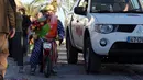 Seorang pria mengenakan kostum badut sambil menaiki sepeda motor mini saat mengikuti Parade Karnaval Clowns di pantai Sesimbra, Lisbon, Spanyol (12/2). (AP Photo / Armando Franca)