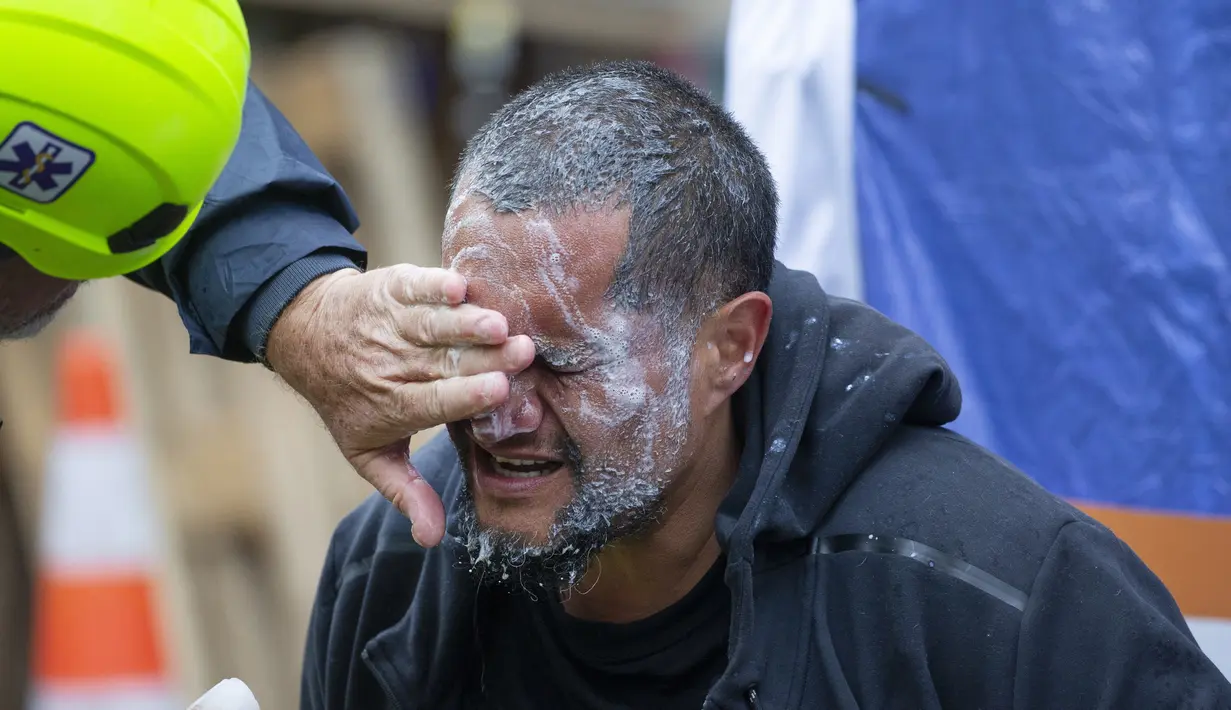 Seorang pengunjuk rasa mendapat perawatan medis setelah disemprot polisi pada protes menentang mandat vaksin virus corona di Wellington, Selandia Baru, Rabu (2/3/2022). Selandia Baru telah melaporkan kurang dari 100 kematian akibat virus. (Mark Mitchell/New Zealand Herald via AP)