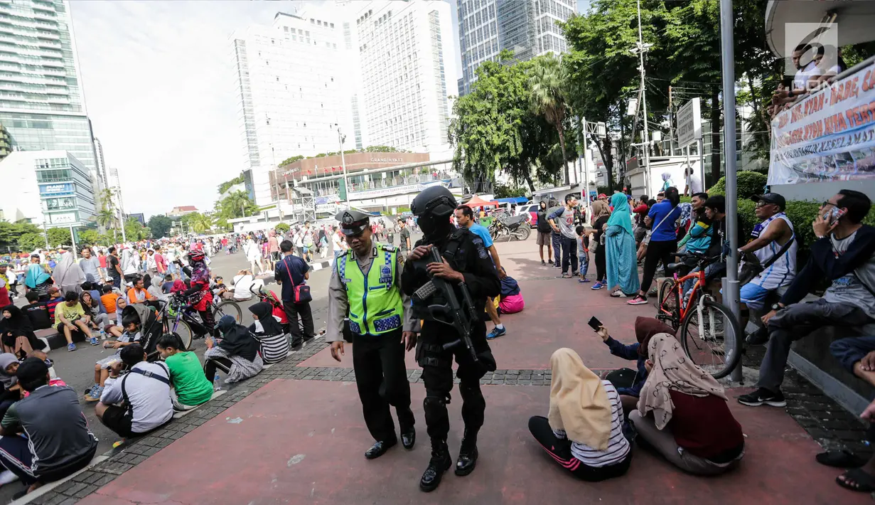 Pasukan Brimob dan polisi lalulintas berjaga saat Car Free Day di kawasan Bunderan HI, Jakarta, Minggu (24/12). Pengamanan tersebut merupakan salah satu rangkaian operasi Lilin 2017. (Liputan6.com/Faizal Fanani)