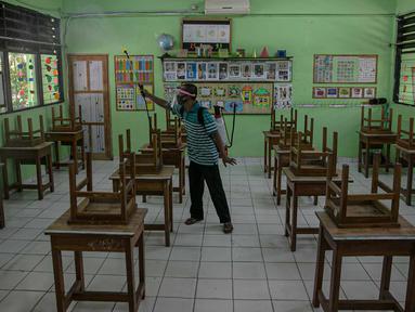 Seorang guru mendisinfeksi kelas yang akan digunakan di SDN Kenari 08, Jakarta, Selasa (6/4/2021). Pemerintah Provinsi DKI Jakarta akan melakukan uji coba pembelajaran tatap muka terbatas di 100 sekolah mulai 7 April hingga 29 April 2021. (Liputan6.com/Faizal Fanani)