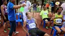 Seorang relawan menyemprotkan air kepada peserta lari lansia 400 meter dalam Elderly Games Nasional di Thailand (25/4). Pertandingan yang diikuti antar lansia ini merupakan yang pertama di Thailand. (AFP/Lillian Suwanrumpha)