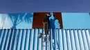 Seorang seniman menyelesaikan pengecatan pagar yang memisahkan antara Meksiko dan Amerika Serikat di Playas Tijuana, Meksiko (10/12). (Reuters/Jorge Duenes)