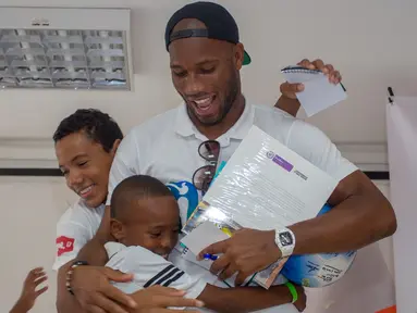 Mantan pemain sepak bola Didier Drogba memeluk anak-anak saat acara amal organisasi internasional Peace and Sport, di Cartagena, Kolombia (19/3). Didier Drogba merupakan pesebak bola dunia dari Pantai Gading. (Cesar Carrion/Colombian Presidency/AFP)