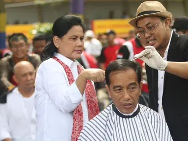 Presiden Joko Widodo disaksikan Ibu Negara Iriana saat mengikuti acara cukur rambut massal di Garut, Jawa Barat, Sabtu (19/1). Jokowi ikut cukur rambut bersama puluhan warga Garut lainnya. (Liputan6.com/Angga Yuniar)