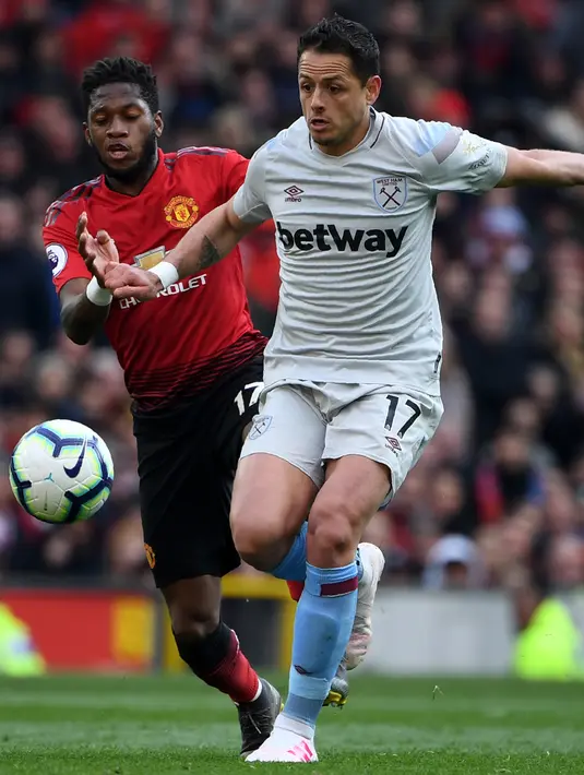 Striker West Ham United, Javier Hernandez berusaha menggiring bola dari kejaran gelandang Manchester United, Fred selama pertandingan lanjutan Liga Inggris di Old Trafford (13/4). MU menang tipis atas West Ham 2-1. (AFP Photo/Paul Ellis)