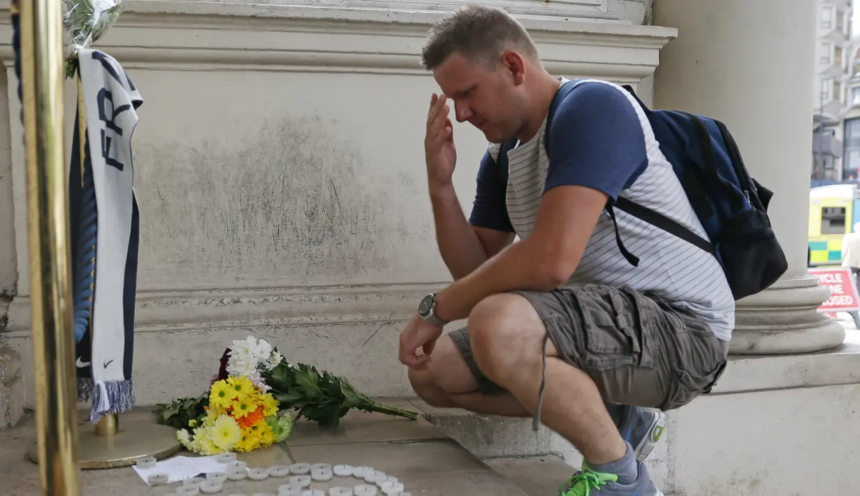 Seorang pria berdoa usai meletakan bunga di luar kedutaan Perancis di London, Inggris (15/7). Karangan bunga tersebut untuk menghormati para korban teror Truk Maut saat perayaan hari Bastille di Nice. (AFP PHOTO/DANIEL Leal-Olivas)