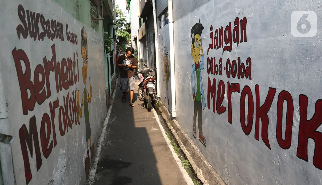 Warga melintas dekat mural kawasan bebas asap rokok di lingkungan RW 06 Kelurahan Kayu Manis, Matraman, Jakarta, Jumat (8/10/2021). Beberapa titik pada kawasan tersebut juga terdapat mural-mural tentang pemberitahuan serta peringatan untuk tidak dan berhenti merokok (Liputan6.com/Herman Zakharia)