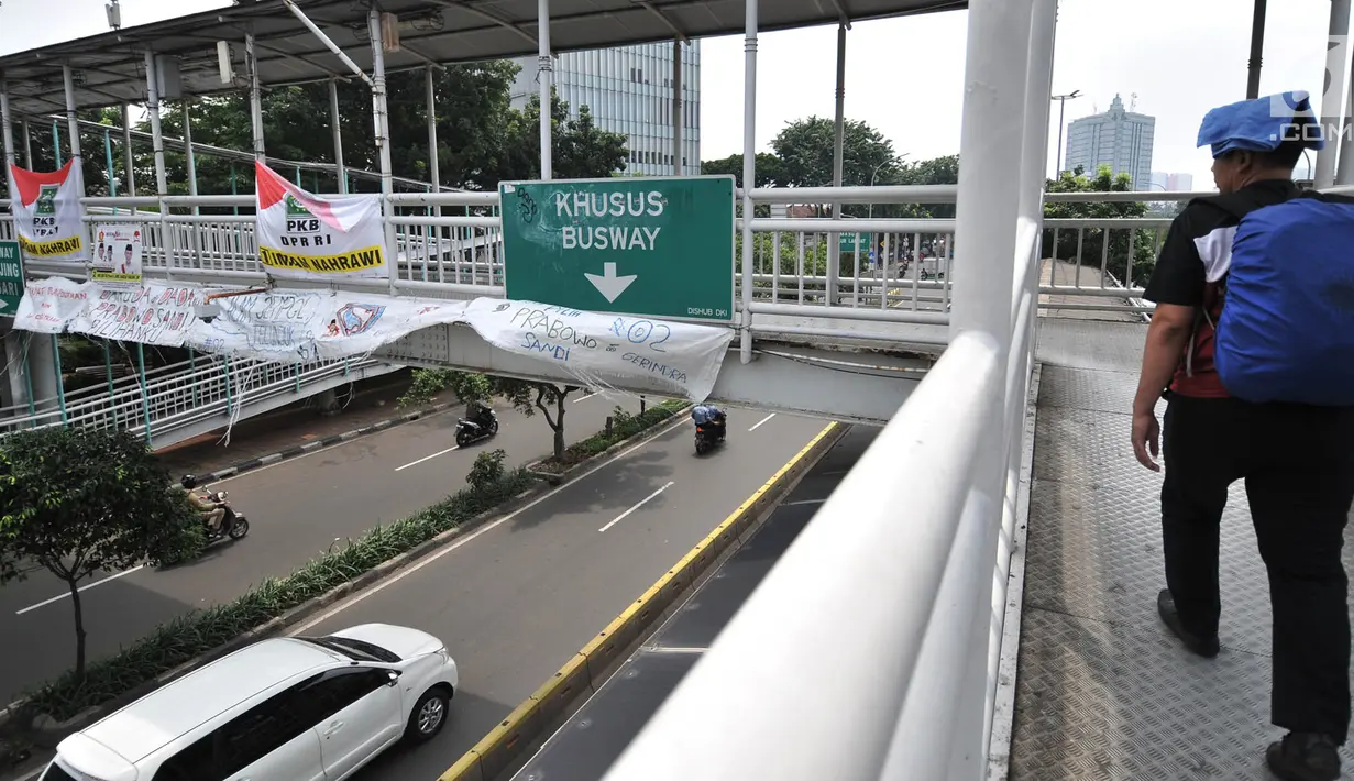 Warga melihat Spanduk Rakyat dukungan Prabowo-Sandiaga yang terpasang di JPO Jakarta, Selasa (9/4). Berbeda dengan spanduk pada umumnya, Spanduk Rakyat merupakan karung bekas yang dibuat oleh pendukung Prabowo-Sandiaga yang ditulis dengan cat atau spidol. (merdeka.com/Iqbal S. Nugroho)
