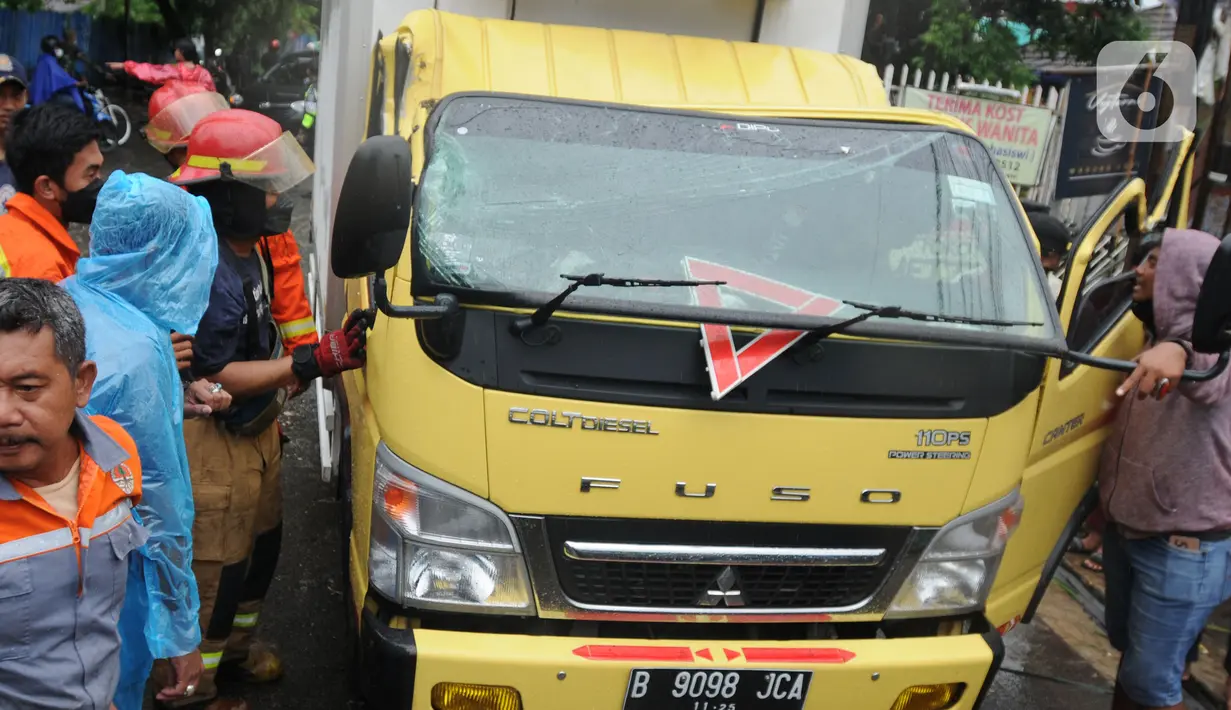 Petugas mengevakuasi truk boks yang rusak parah akibat tertimpa pohon tumbang di Jalan Padjajaran, Kota Tangerang Selatan, Banten, Sabtu (5/3/2022). Dua unit kendaraan dan dua pengendara motor yang sedang melintas tertimpa pohon tumbang saat angin kencang melanda Jabotabek. (merdeka.com/Arie Basuki)