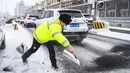 Polisi menyebarkan abu di jalan agar tidak terlalu licin di tengah hujan salju di Urumqi, ibu kota Daerah Otonom Uighur Xinjiang, China barat laut, pada 19 November 2020. Hujan salju yang terus turun selama berhari-hari telah menyebabkan jalanan di Kota Urumqi basah dan licin. (Xinhua/Wang Fei)