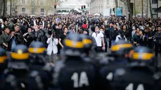 Polisi anti huru hara berjaga didepan para demonstran di Place de la Republique, di Paris, Prancis (2/4). Setidaknya 6.000 orang yang tergabung dalam komunitas etnis China di Prancis turun ke jalanan kota Paris menggelar aksi protes. (AFP/Benjamin Cremel)