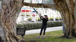 Seorang wanita berolahraga di sebuah taman di pinggiran timur Sydney, pada 14 September 2021. Pelatih kebugaran telah mengubah taman kawasan tepi laut di Rushcutters Bay Sydney menjadi gym luar ruangan untuk menyiasati pembatasan lockdown karena pandemi covid-19. (AP/Mark Baker)