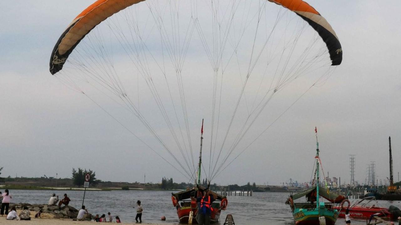 Selain berwisata dengan perahu di Pantai Ancol, pengunjung juga dapat menikmati serunya terbang bak&nbsp;paralayang  dengan parasut yang ditarik speedboat.&nbsp;Foto: Liputan6.com / Herman Zakharia