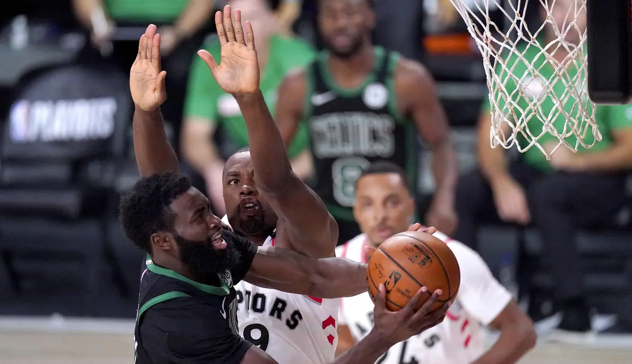 Pebasket Boston Celtics, Jaylen Brown, berebut bola dengan pebasket Toronto Raptors pada semifinal playoff NBA wilayah timur di AdventHealth Arena, Sabtu (12/9/2020). Boston Celtics menang 92-87 atas Toronto Raptors.  (AP Photo/Mark J. Terrill)