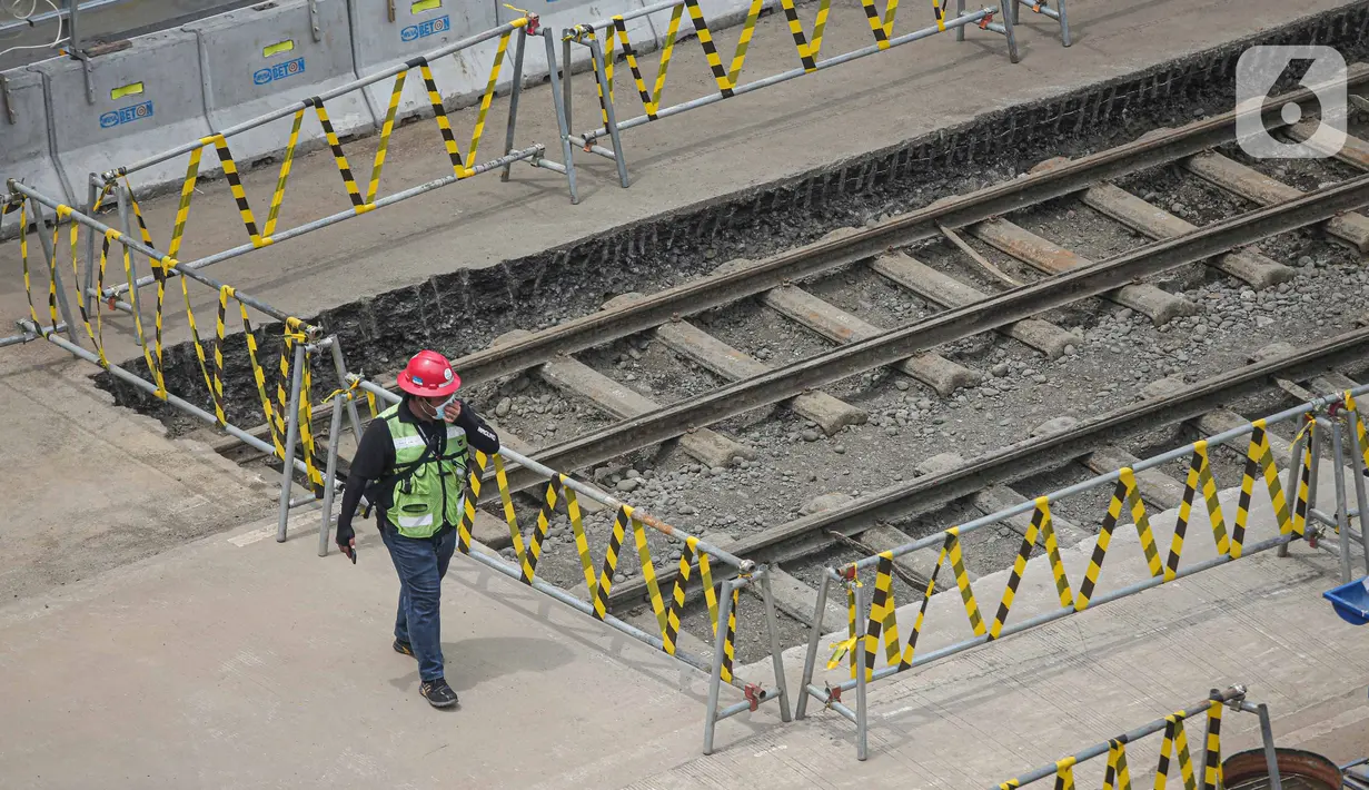 Petugas berjaga dekat lokasi ditemukannya rel trem di proyek pembangunan MRT Jakarta fase 2A paket kontrak atau CP 203 Glodok-Kota, Jakarta, Selasa (28/12/2021). PT MRT Jakarta menyatakan rel trem peninggalan Belanda tersebut akan dipindahkan dan disimpan. (Liputan6.com/Faizal Fanani)