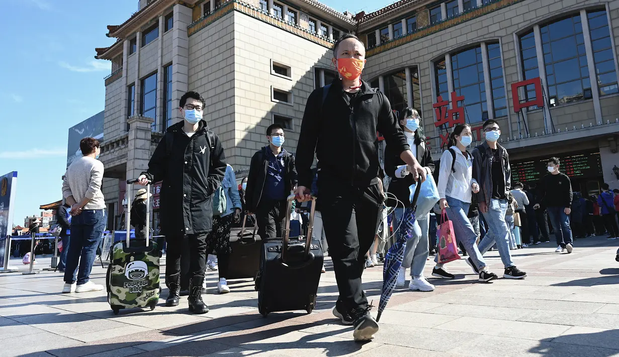 Orang-orang tiba di stasiun kereta api Beijing pada hari terakhir libur nasional "golden week", Kamis (7/10/2021). Hari libur selama 8 hari pada 1-7 Oktober tersebut menjadi hari libur terbesar kedua di Cina setelah tahun  baru. (JADE GAO / AFP)