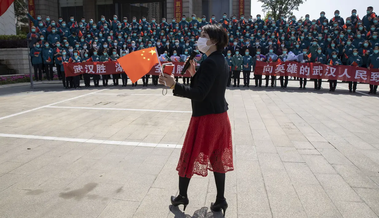 Seorang wanita memegang bendera China saat upacara perpisahan untuk kelompok petugas medis terakhir yang datang dari luar Wuhan dalam membantu kota selama wabah virus corona COVID-19 di Wuhan, Provinsi Hubei, China, Rabu (15/4/2020). Wuhan menjadi pusat penyebaran COVID-19. (AP Photo/Ng Han Guan)