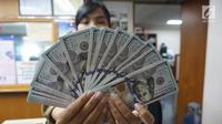 Teller menunjukkan mata uang dolar AS di penukaran uang di Jakarta, Rabu (10/7/2019). Nilai tukar rupiah terhadap dolar Amerika Serikat (AS) ditutup stagnan di perdagangan pasar spot hari ini di angka Rp 14.125. (Liputan6.com/Angga Yuniar)