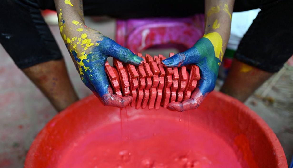 Seorang pembuat tembikar mewarnai lampu tanah jelang Festival Diwali di sepanjang pinggir jalan di New Delhi, India, 18 Oktober 2022. Festival Diwali atau dalam agama Hindu berarti Festival Cahaya melambangkan kemenangan baik atas keburukan, dan lampu atau pelita dinyalakan sebagai tanda perayaan serta harapan umat manusia. (Sajjad HUSSAIN/AFP)