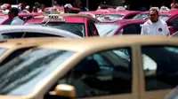 Sopir taksi bersama deretan mobil taksi yang  diparkir pada saat protes regulasi jasa antara taksi konvensional dan online di Mexico City, Meksiko (12/10). Sejak adanya taksi online, penghasilan taksi konvensional berkurang.  (Reuters/Carlos Jasso)