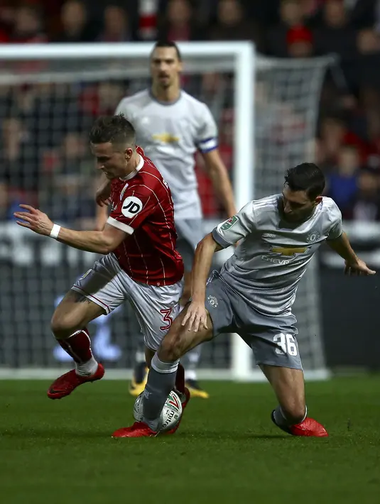 Pemain Bristol City, Joe Bryan berebut bola dengan pemain Manchester United, Matteo Darmian pada perempat final Piala Liga Inggris di Ashton Gate, Kamis (21/12). MU tersingkir dari Piala Liga Inggris setelah takluk 1-2. (Geoff CADDICK / AFP)