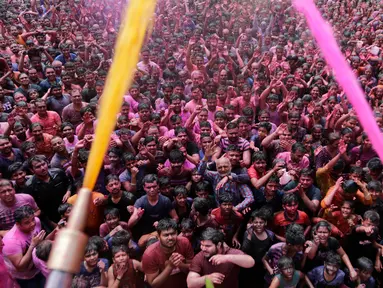 Umat Hindu bersorak ketika bubuk berwarna dan air disemprotkan kepada mereka saat Festival Holi di Kuil Swaminarayan, Ahmedabad, India, Selasa (10/3/2020). Festival Holi menandai datangnya musim semi di India. (AP Photo/Ajit Solanki)