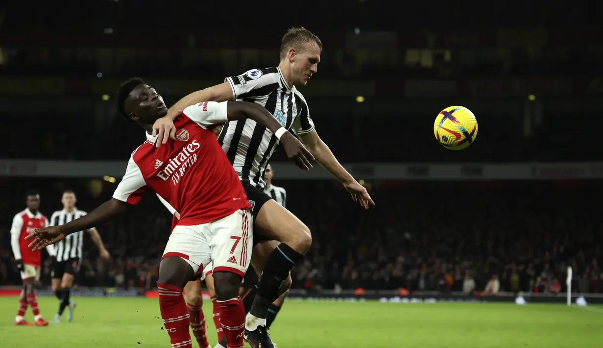 Gelandang Arsenal, Bruno Saka berebut bola denganpemain Newcastle United, Dan Burn selama pertandingan lanjutan Liga Inggris di stadion Emirates di London, Rabu (4/1/2023). Hasil ini membuat Arsenal kini mengumpulkan 44 poin di puncak klasemen dan Newcastle berada di posisi ketiga dengan 35 poin. (AP Photo/Ian Walton)