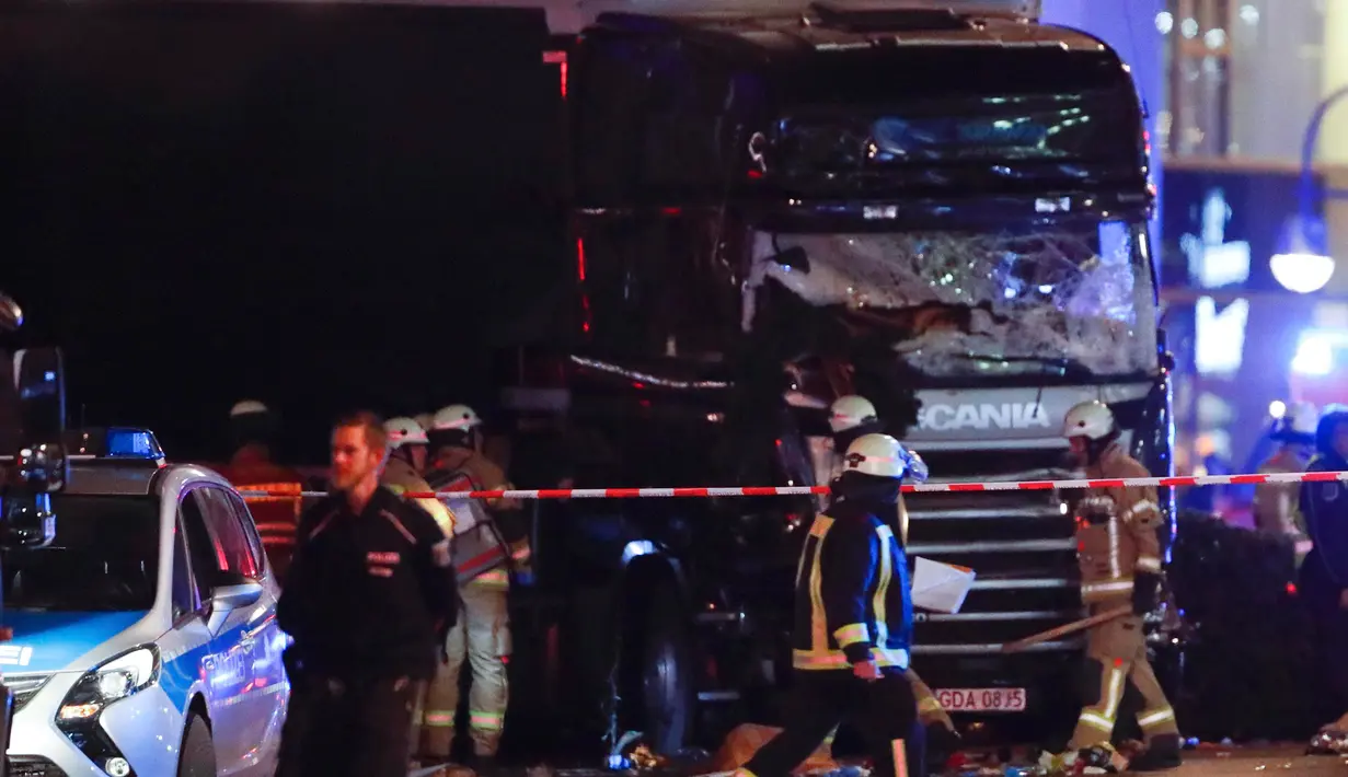 Petugas pemadam berjalan di depan truk yang menabrak kerumunan orang di sebuah pasar Natal di pusat Kota Berlin, Jerman, Senin (19/12). Kepolisian belum dapat memastikan identitas sopir truk berpelat nomor Polandia tersebut. (REUTERS/Fabrizio Bensch)