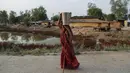 Seorang wanita desa India membawa air berjalan dengan bantuan tongkat di desa Ganeshpur, di distrik Sonbhadra negara bagian Uttar Pradesh, India, Minggu (11/4/2021).  (AP Photo/Rajesh Kumar Singh)