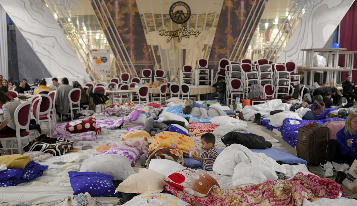 Pengungsi yang melarikan diri dari invasi Rusia dari negara tetangga Ukraina duduk di dalam ballroom yang diubah menjadi tempat penampungan pengungsi darurat di hotel & spa bintang 4, di Suceava, Rumania, 4 Maret 2022. (AP Photo/Andreea Alexandru)