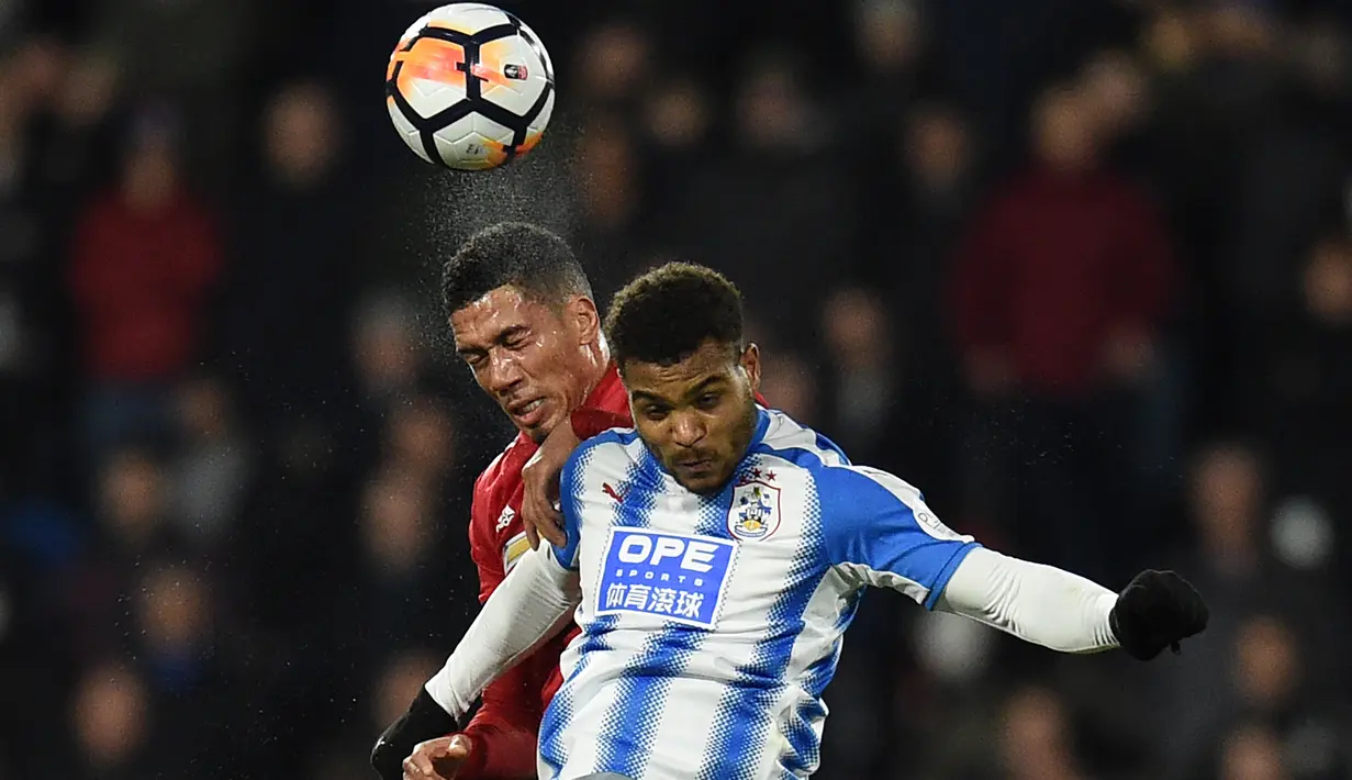 Duel pemain Huddersfield, Steve Mounie (kanan) dan bek Manchester United, Chris Smalling pada putaran kelima Piala FA di John Smith stadium, Huddersfield, (17/2/2018). Manchester United menang 2-0. (AFP/Oli Scarff)