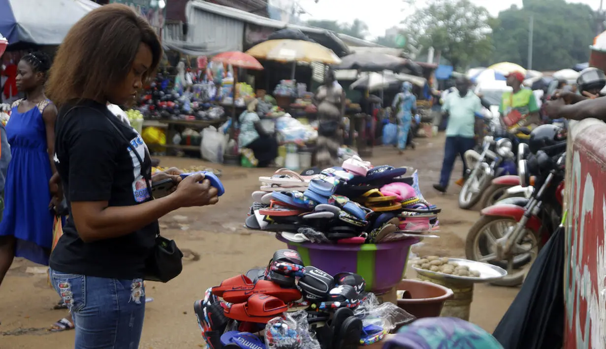 Seorang perempuan berbelanja di pasar Kaporo di Conakry, Guinea, Senin (13/9/2021). Pasukan elit militer Guinea melakukan kudeta dan menangkap Presiden Alpha Conde pada Minggu, 5 September lalu. (AP Photo/ Sunday Alamba)