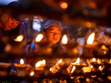 Seorang anak laki-laki menyalakan lampu minyak saat Festival Kuse Aunsi di Kuil Gokarneshwor, Kathmandu, Nepal, Kamis (14/9/2023). Kuse Aunsi adalah festival di mana para ayah, baik yang masih hidup maupun yang sudah meninggal, dihormati. (AP Photo/Niranjan Shrestha)