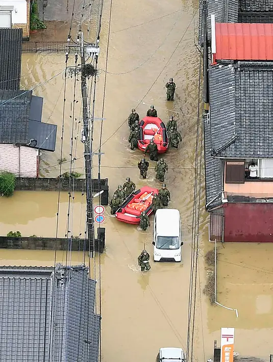 Pasukan Bela Diri Jepang menyusuri banjir saat operasi penyelamatan di Takeo, Prefektur Saga, Jepang, Rabu (28/8/2019). Perintah evakuasi 240 ribu warga di Kyushu dan sekitarnya dikeluarkan usai seorang warga dilaporkan tewas akibat terkena imbas hujan deras di Kota Saga. (Kyodo News via AP)