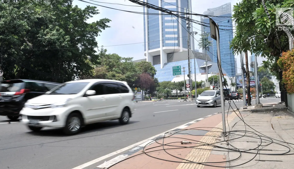 Kendaraan melintas dekat kabel listrik yang menjuntai di Jalan Haji Agus Salim, Jakarta, Minggu (9/9). Instalasi kabel yang menjuntai ke jalan akibat tersangkut truk itu dapat membahayakan warga dan pengendara yang melintas (Merdeka.com/ Iqbal S. Nugroho)