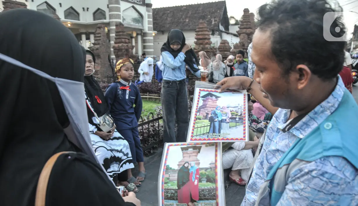 Fotografer keliling menawarkan jasanya kepada peziarah Makam Sunan Kudus, Kauman, Kabupaten Kudus, Jawa Tengah, Rabu (30/3/2022). Arka (45) anggota Paguyuban Fotografer Menara Kudus mengaku pendapatan dari jasa foto peziarah meningkat menjelang bulan Ramadan. (merdeka.com/Iqbal S. Nugroho)