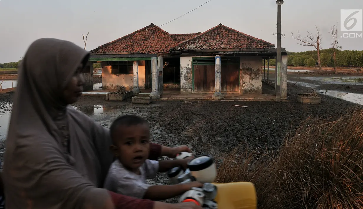 Warga melintasi rumah rusak yang ditinggalkan penghuni di Kampung Beting. Kini warga hanya bisa pasrah dengan kelanjutan dampak abrasi yang akan terjadi dan berharap pemerintah Kabupaten Bekasi sadar dan segera mengatasi langgengnya abrasi di pesisir utara Bekasi itu. (merdeka.com/Iqbal S Nugroho)