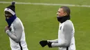 Penyerang PSG, Kylian Mbappe (kanan) tertawa bersama rekannya saat mengikuti sesi latihan di Saint-Germain-en-Laye, Prancis (13/2). PSG akan bertanding melawan Real Madrid di babak 16 besar Liga Champions. (AFP Photo/Lionel Bonaventure)