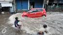 Sejumlah anak bermain dengan gelombang air yang terdorong oleh kendaraan saat melintasi banjir, Jakarta, Rabu (20/7). Akibat hujan deras kawasan Kemang Utara tergenang air 60cm sampai 1 meter. (Liputan6.com/Yoppy Renato)
