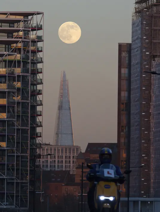 The Wolf Moon, bulan purnama pertama tahun ini, muncul di belakang The Shard di pusat kota London, Senin (17/1/2022). Wolf Moon atau disebut juga Bulan purnama Serigala adalah sebutan untuk bulan purnama pertama di Januari. (Justin TALLIS / AFP)