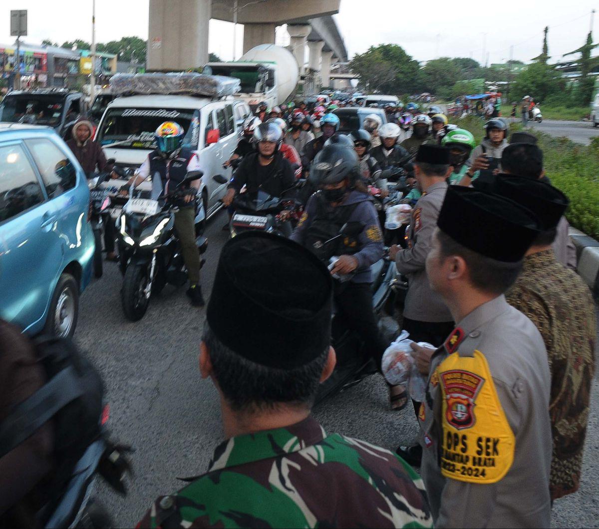 Sejumlah prajurit TNI dan petugas kepolisian dari Polsek Cakung membagikan takjil gratis kepada warga yang melintas di Jalan Raya Cakung, Jakarta Timur, Kamis (21/3/2024). Ada 300 paket takjil yang dibagikan gratis&nbsp;menjelang waktu berbuka puasa.&nbsp